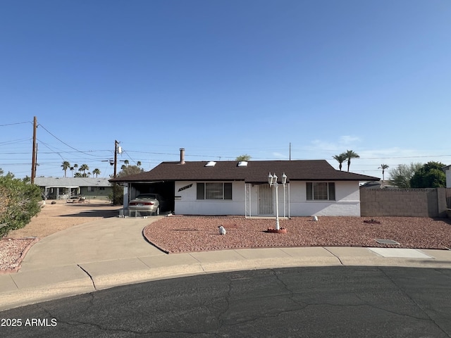 view of front of home with a shingled roof, fence, an attached carport, and driveway