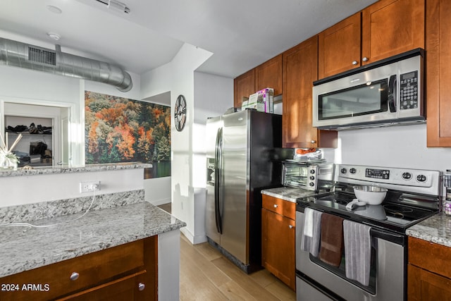 kitchen featuring appliances with stainless steel finishes, light stone counters, and light hardwood / wood-style floors