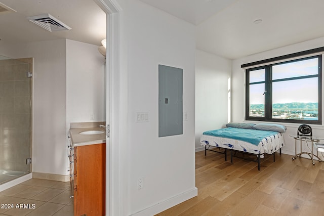 bedroom with sink, electric panel, and light wood-type flooring