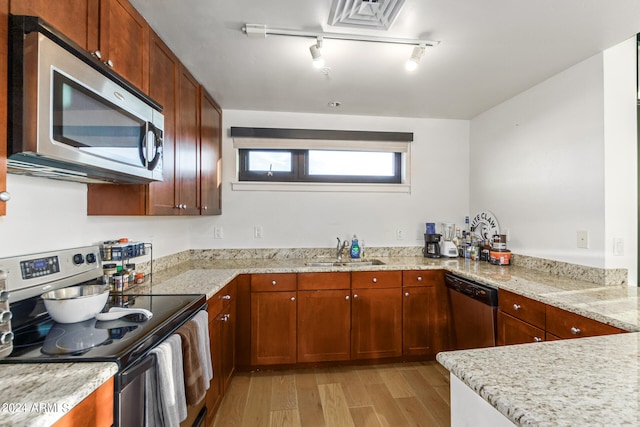 kitchen with appliances with stainless steel finishes, sink, light wood-type flooring, kitchen peninsula, and light stone counters