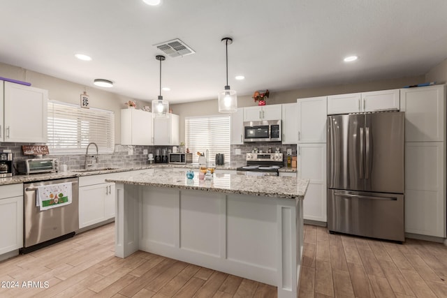 kitchen with white cabinetry, stainless steel appliances, light hardwood / wood-style floors, and a kitchen island