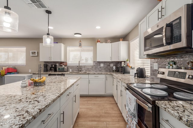 kitchen featuring white cabinetry, appliances with stainless steel finishes, sink, and pendant lighting