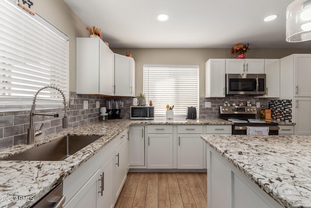 kitchen featuring white cabinetry, appliances with stainless steel finishes, backsplash, sink, and light hardwood / wood-style flooring
