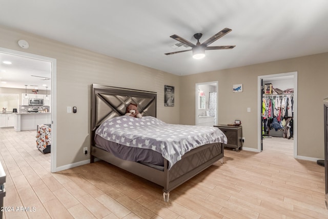 bedroom with a closet, a walk in closet, ceiling fan, and light hardwood / wood-style flooring