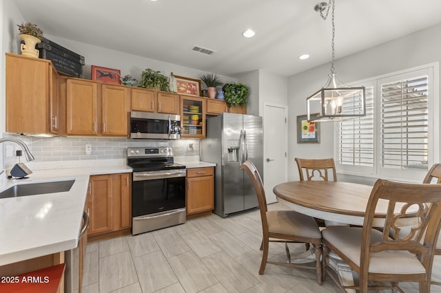 kitchen featuring stainless steel appliances, hanging light fixtures, sink, and decorative backsplash