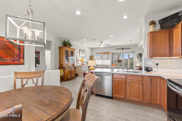 kitchen with sink, decorative light fixtures, appliances with stainless steel finishes, ceiling fan with notable chandelier, and decorative backsplash