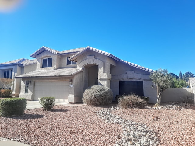 mediterranean / spanish-style home with concrete driveway, an attached garage, a tiled roof, and stucco siding