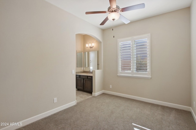 unfurnished bedroom featuring ensuite bathroom, ceiling fan, and light colored carpet