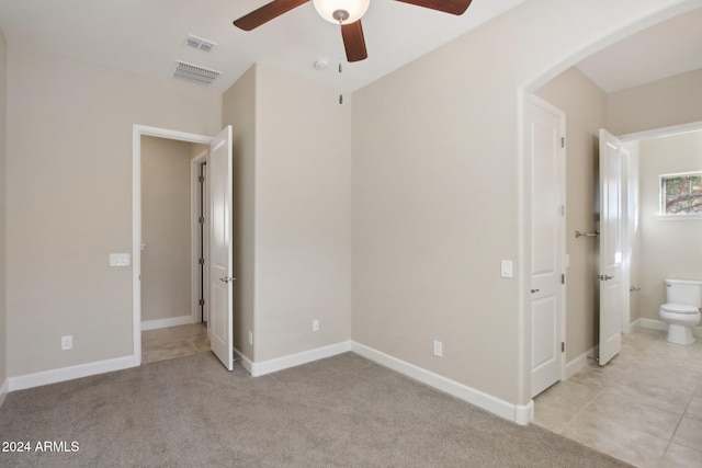 unfurnished bedroom with ceiling fan, light colored carpet, and connected bathroom