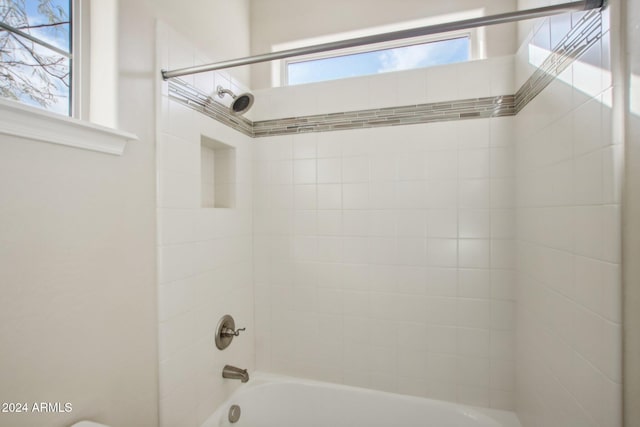 bathroom featuring a healthy amount of sunlight and tiled shower / bath