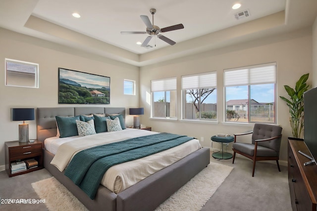 carpeted bedroom featuring a raised ceiling and ceiling fan