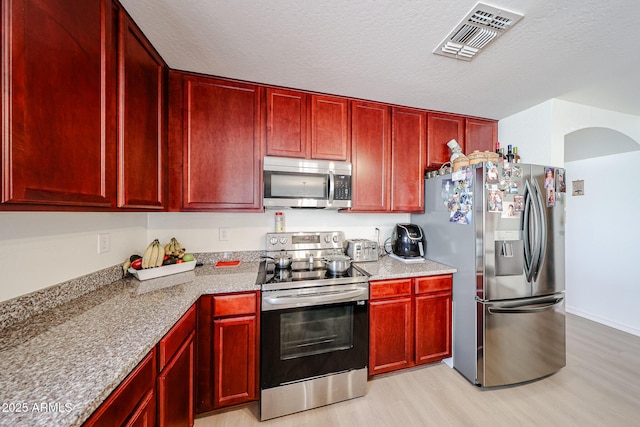 kitchen featuring visible vents, appliances with stainless steel finishes, and dark brown cabinets