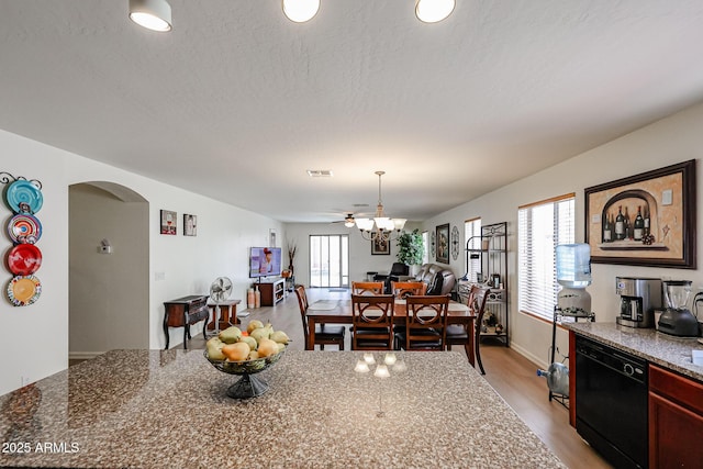 dining area with arched walkways, visible vents, and light wood-style flooring
