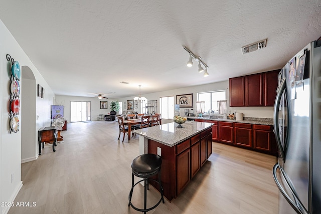 kitchen featuring freestanding refrigerator, visible vents, light wood finished floors, and reddish brown cabinets