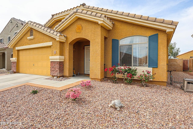 view of front of house with a tiled roof, driveway, a garage, fence, and stucco siding