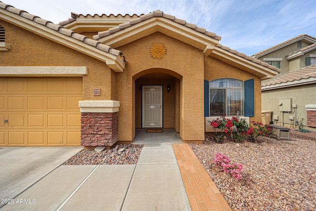 property entrance featuring a garage, stucco siding, driveway, and a tiled roof