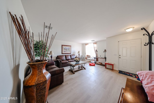 living area featuring baseboards, visible vents, and light wood finished floors
