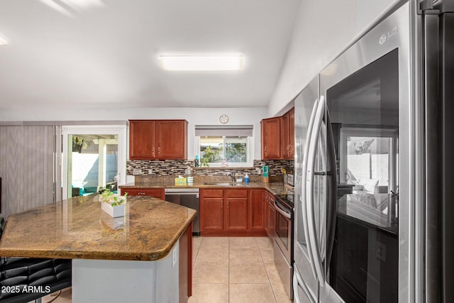1201 E Campbell Ave, Gilbert, AZ 85234 - kitchen with stainless steel appliances, decorative backsplash, a kitchen island, brown cabinets, and light tile patterned floors