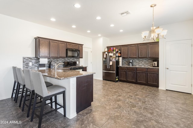 kitchen featuring pendant lighting, black appliances, dark stone countertops, a notable chandelier, and kitchen peninsula