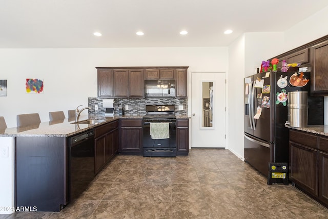 kitchen with stone counters, a kitchen bar, sink, and black appliances