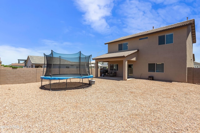 back of house with a trampoline and a patio