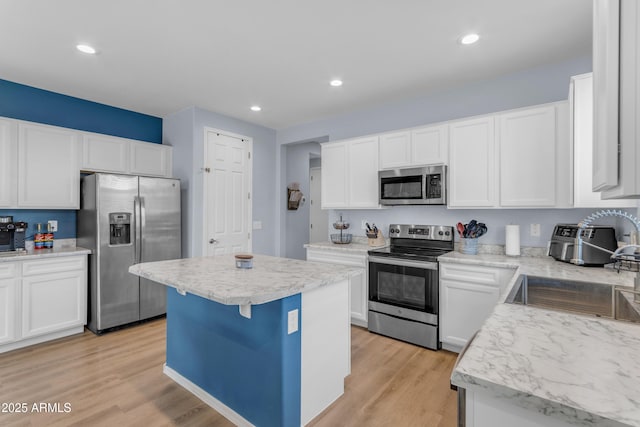 724 S 11th St, Coolidge, AZ 85128 - kitchen featuring stainless steel appliances, a kitchen island, light countertops, light wood finished floors, and white cabinets