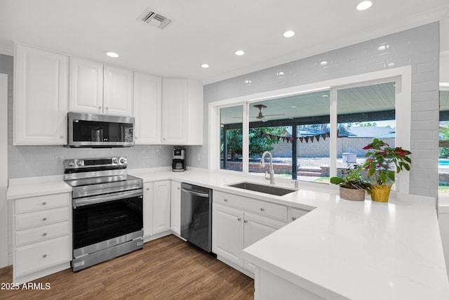 2607 E Mercer Ln, Phoenix, AZ 85028 - kitchen with appliances with stainless steel finishes, white cabinets, recessed lighting, wood finished floors, and a peninsula