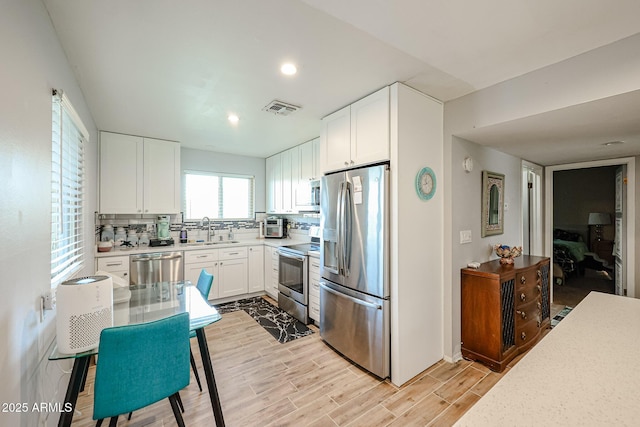 kitchen with backsplash, sink, white cabinets, and appliances with stainless steel finishes