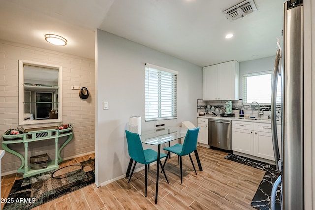 kitchen with appliances with stainless steel finishes, light hardwood / wood-style flooring, white cabinetry, and sink