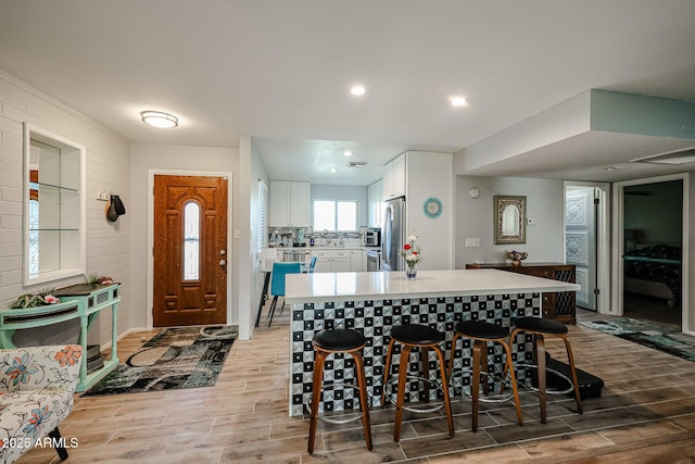 kitchen featuring a breakfast bar, a center island, white cabinetry, and appliances with stainless steel finishes