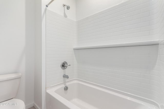 bathroom featuring tiled shower / bath combo and toilet