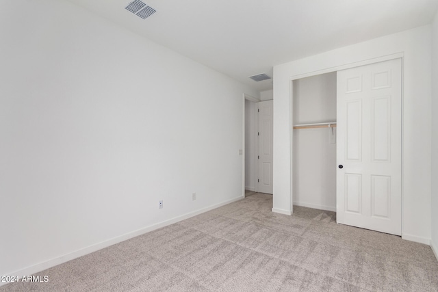 unfurnished bedroom with light carpet and a closet