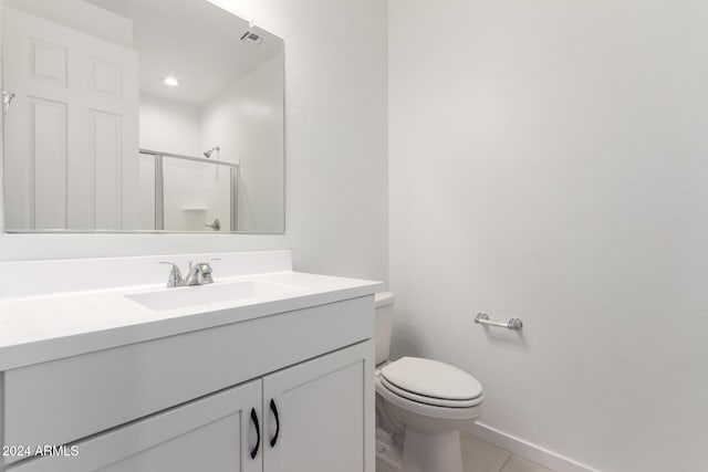 bathroom with tile patterned floors, vanity, toilet, and a shower with door