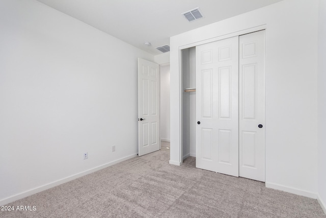 unfurnished bedroom featuring light colored carpet and a closet