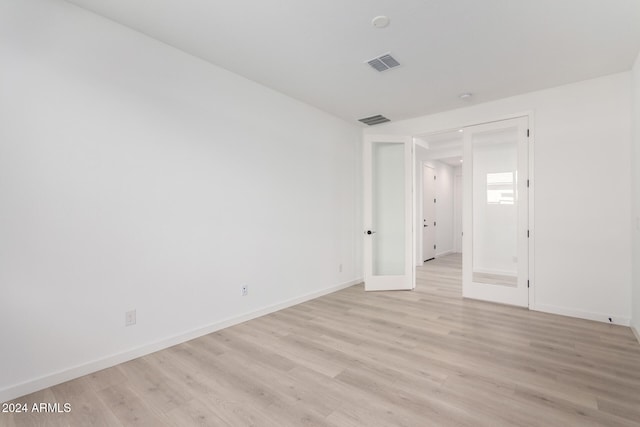 spare room featuring french doors and light hardwood / wood-style floors