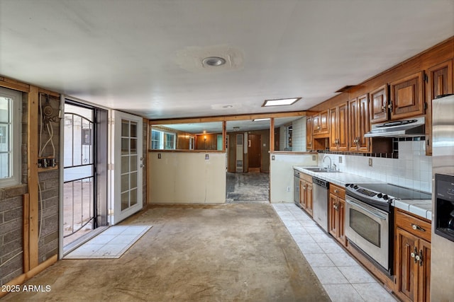 kitchen with tasteful backsplash, under cabinet range hood, tile countertops, stainless steel appliances, and a sink