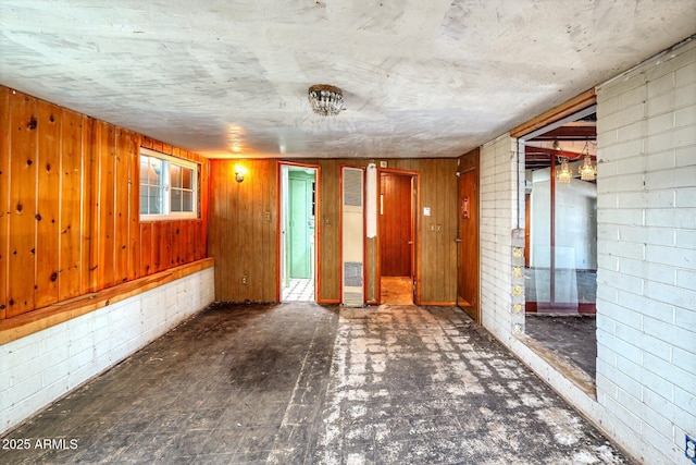 spare room with wood walls and concrete block wall