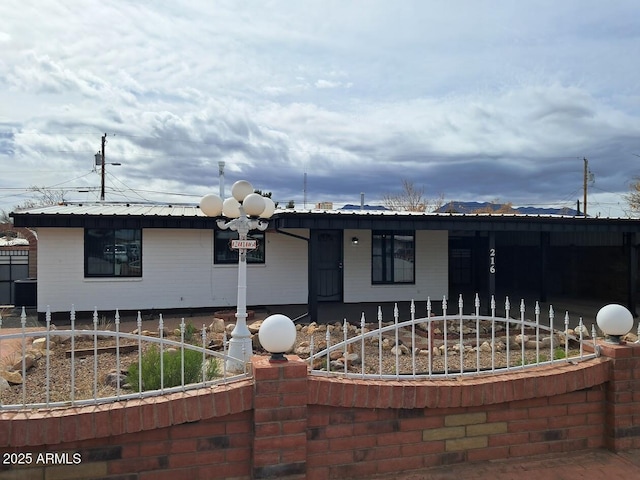 ranch-style house featuring metal roof and fence