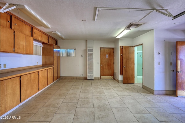 kitchen featuring brown cabinetry, visible vents, a textured ceiling, and light tile patterned flooring