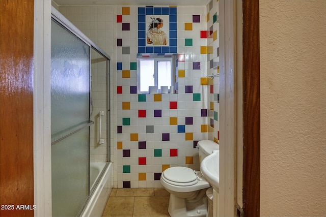 bathroom featuring a textured wall, enclosed tub / shower combo, toilet, and tile patterned flooring