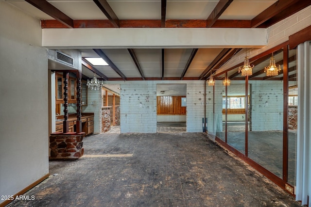 interior space with a chandelier, beam ceiling, brick wall, and visible vents