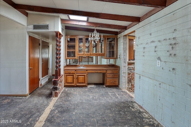 kitchen featuring beam ceiling, hanging light fixtures, glass insert cabinets, brown cabinets, and a chandelier