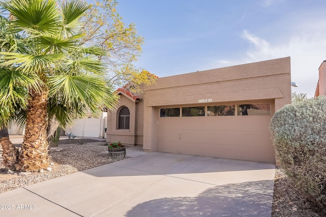 view of front of property featuring driveway, a tiled roof, an attached garage, and stucco siding