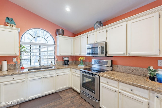 kitchen featuring lofted ceiling, stainless steel appliances, a sink, white cabinets, and dark wood finished floors