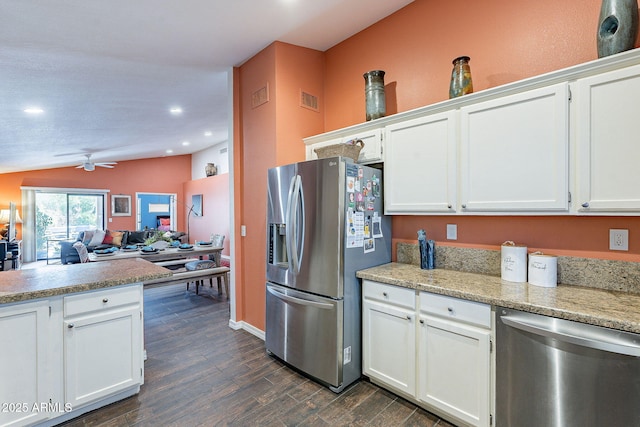 kitchen featuring dark wood-type flooring, visible vents, white cabinets, vaulted ceiling, and appliances with stainless steel finishes