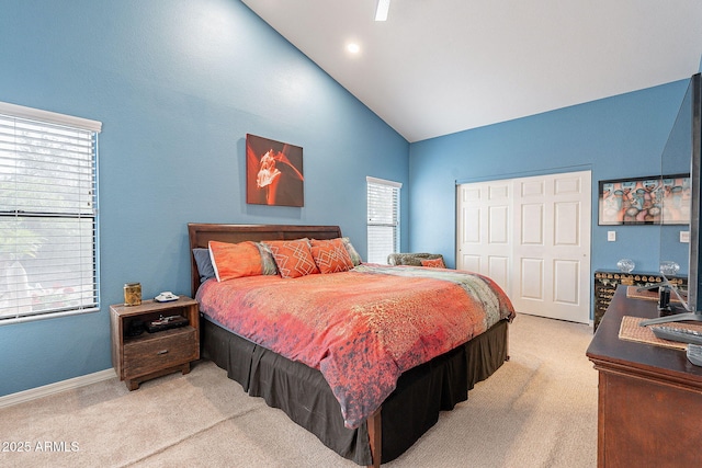 bedroom with vaulted ceiling, a closet, baseboards, and light colored carpet