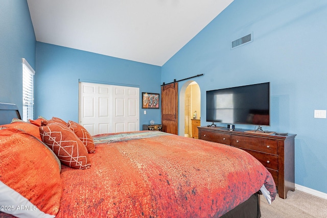 carpeted bedroom featuring high vaulted ceiling, a barn door, visible vents, baseboards, and a closet