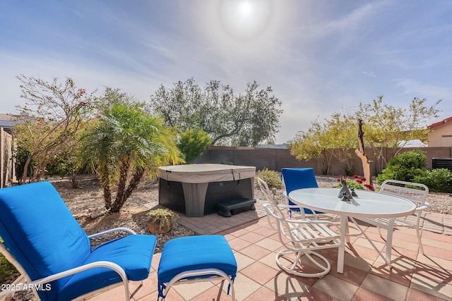 view of patio with outdoor dining area, a fenced backyard, and a hot tub