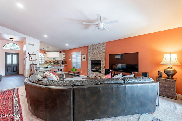 living room with lofted ceiling, ceiling fan, a large fireplace, visible vents, and baseboards