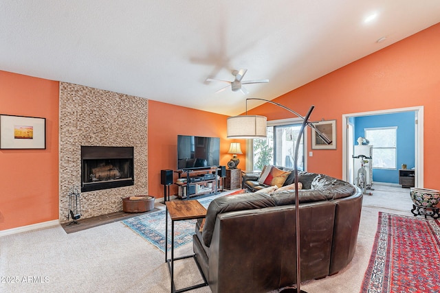 carpeted living area featuring lofted ceiling, a large fireplace, ceiling fan, and baseboards